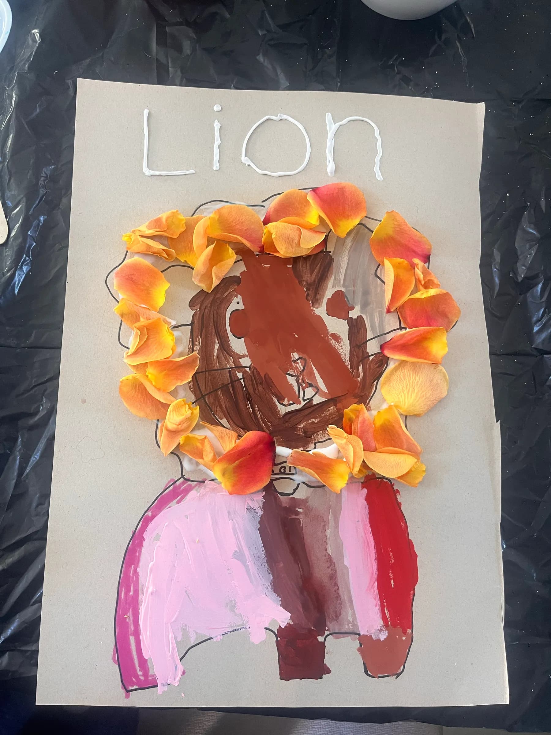 Paper-petal lion collage with an orange mane, made by a young student